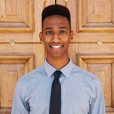 headshot of student standing in front of a wooden door